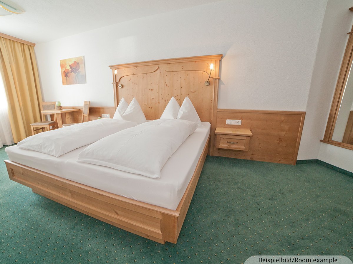 Bild zeigt ein großzügiges Schlafzimmer mit Doppelbett und einen kleinen Sitzbereich