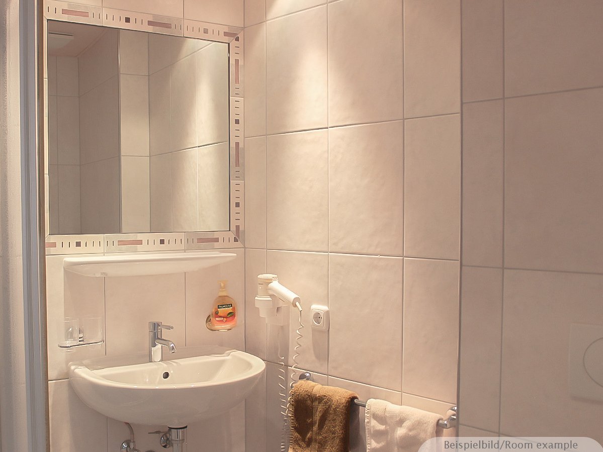 Bild zeigt ein Badezimmer mit Waschbecken, Handtuchhalterung und Föhn