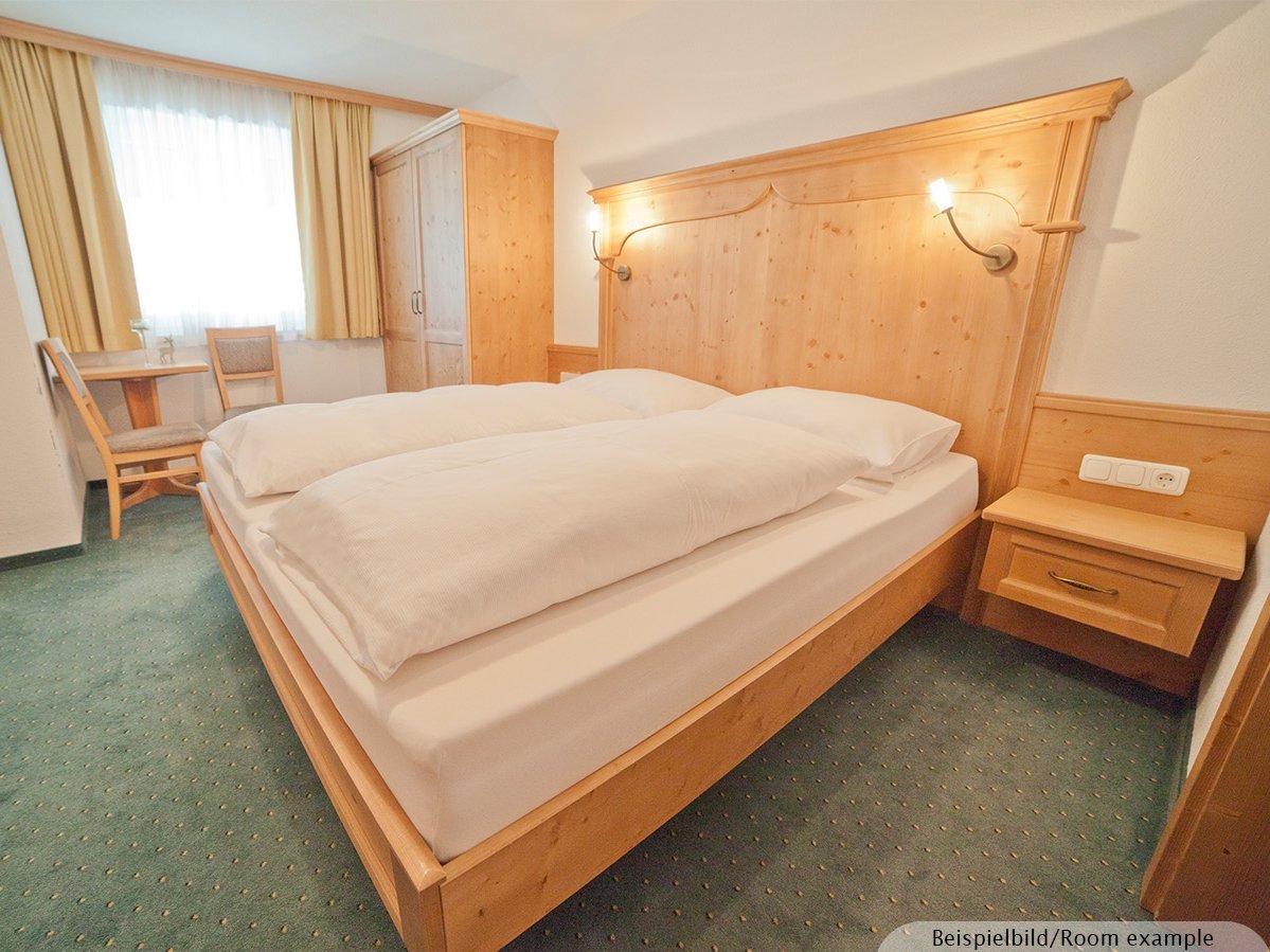 Das Bild zeigt ein goßzügiges und helles Schlafzimmer mit einem Doppelbett und großem Fenster