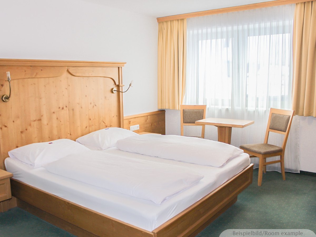 Bild zeigt ein Schlafzimmer mit Doppelbett, einem großen Fenster und einer Sitzecke