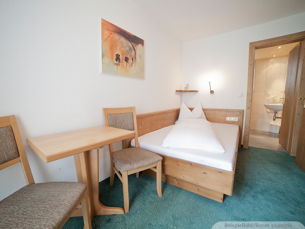 Bild zeigt ein Schlafzimmer mit einer Sitzecke und eine offene Tür zum Badezimmer