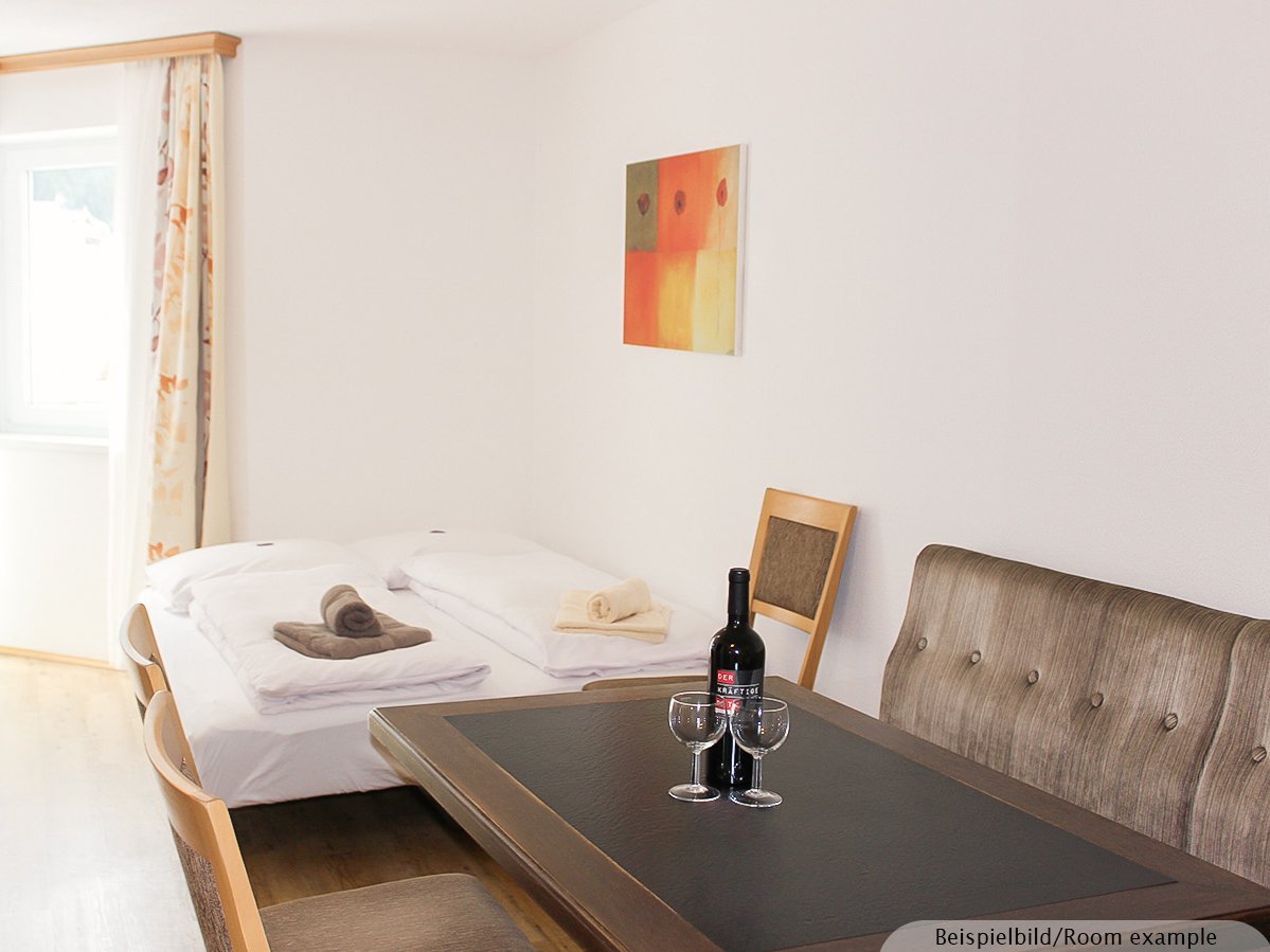 Bild zeigt einen Essbereich mit ausgeklappter Schlafcouch und Fenster im Hintergrund